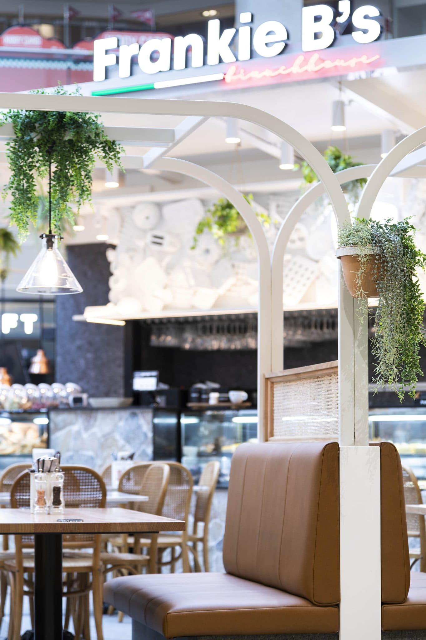 Frankie B's Brunch House seating area with brown leather booths and greenery.