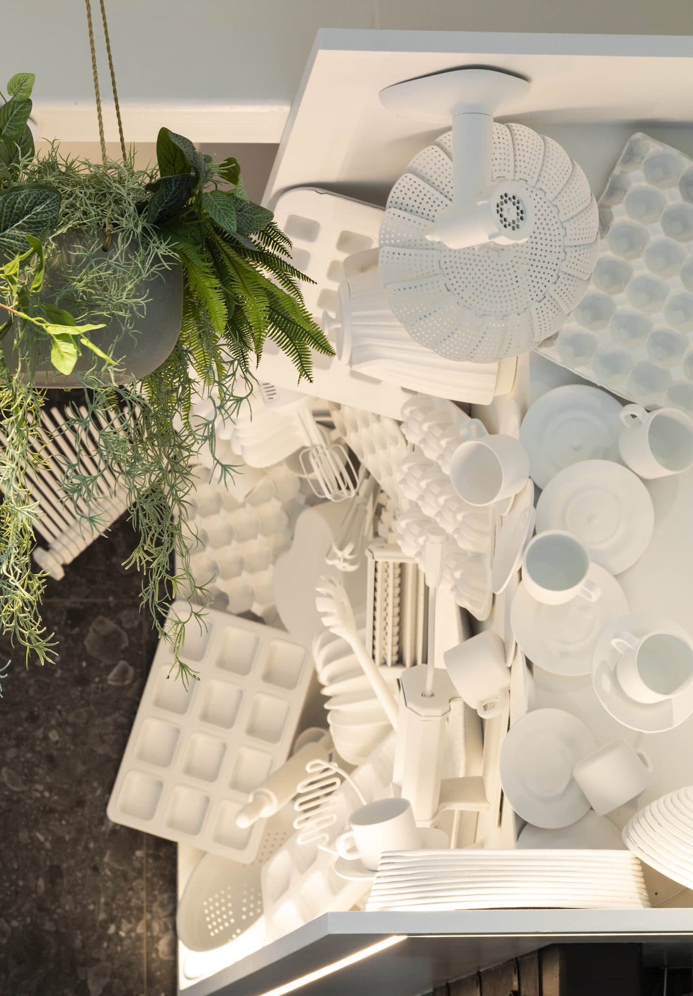 Artistic arrangement of white kitchen utensils and molds at Frankie B's Brunch House, with green foliage in the corner