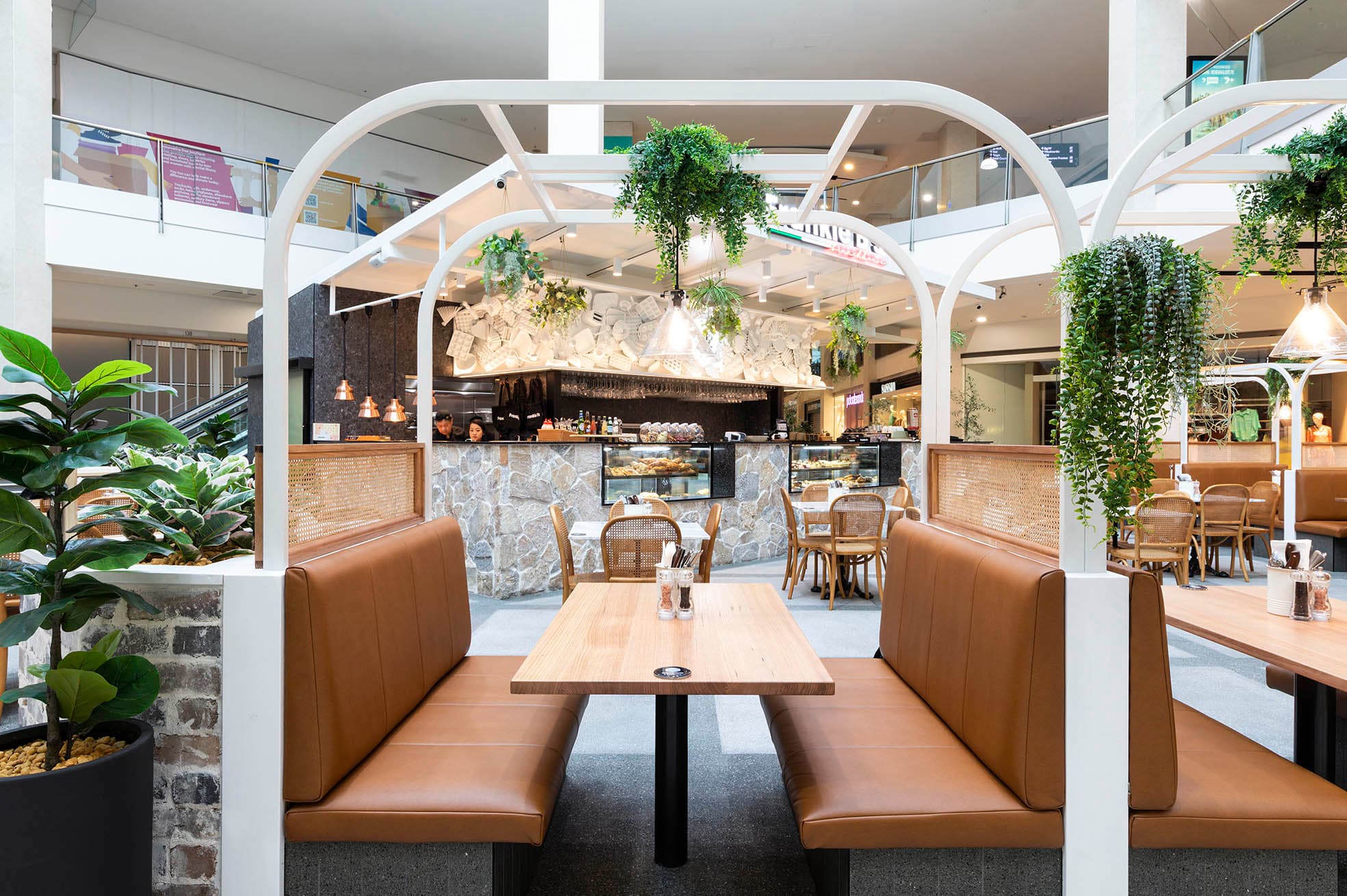 Frankie B's Brunch House seating area with brown leather booths and greenery.