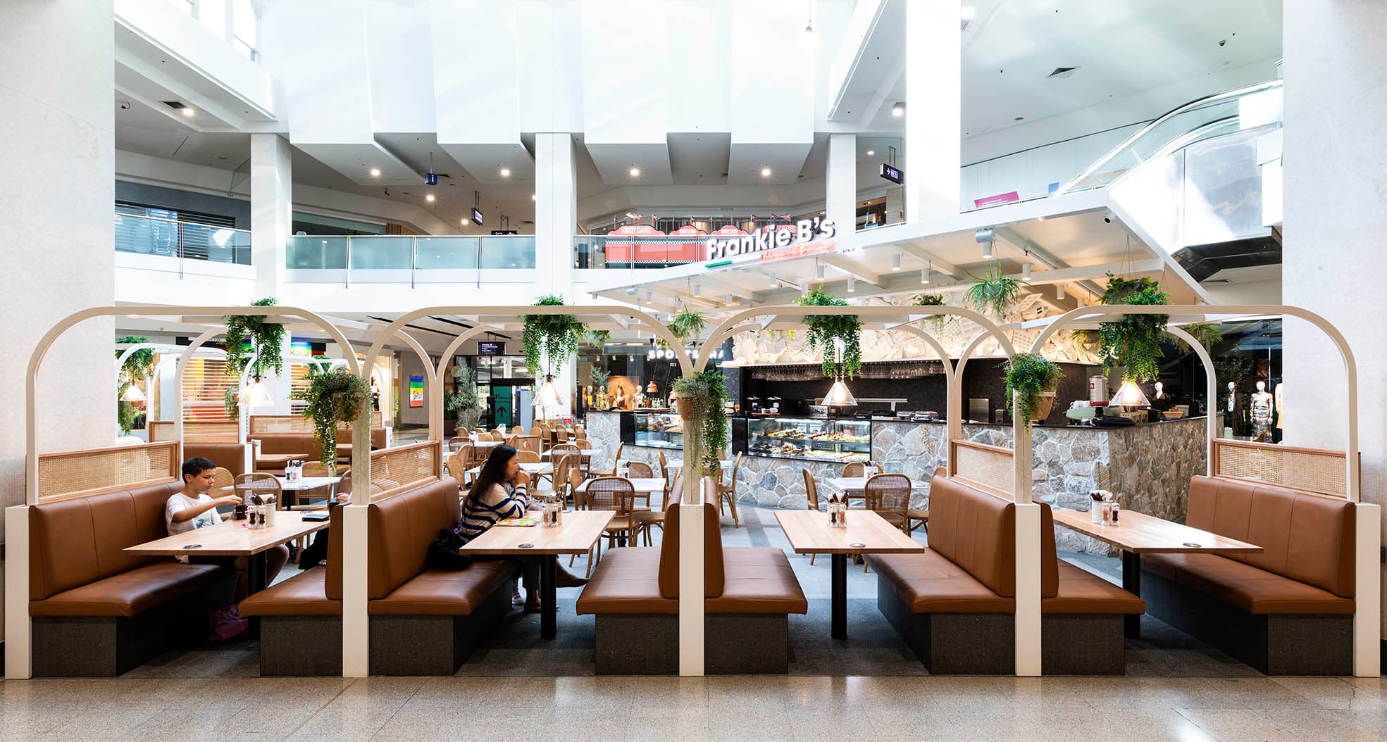 Frankie B's Brunch House seating area with brown leather booths and greenery, located inside a shopping mall