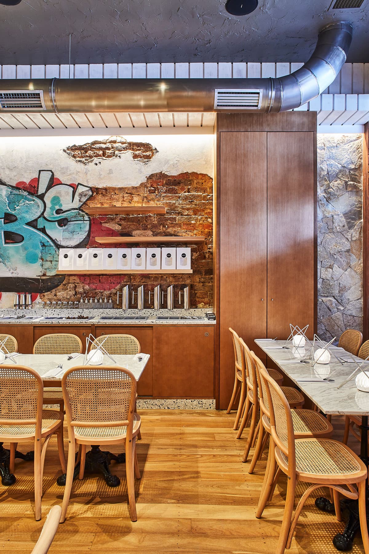 Interior seating area at Frankie B's featuring a section of wall with artistic graffiti, exposed brick, and shelves with decor items.