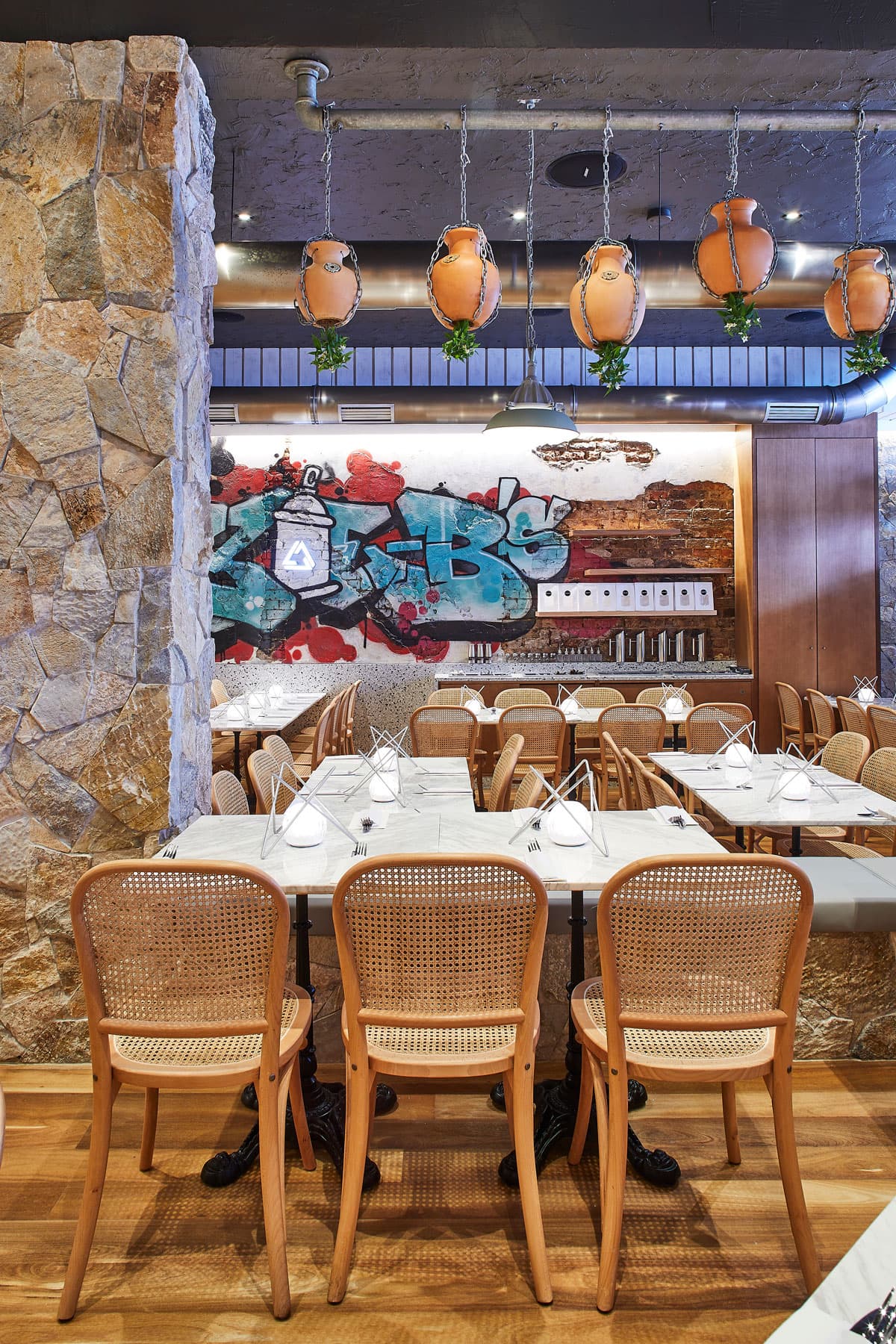 Frankie B's dining area with hanging terracotta pots and graffiti wall art.