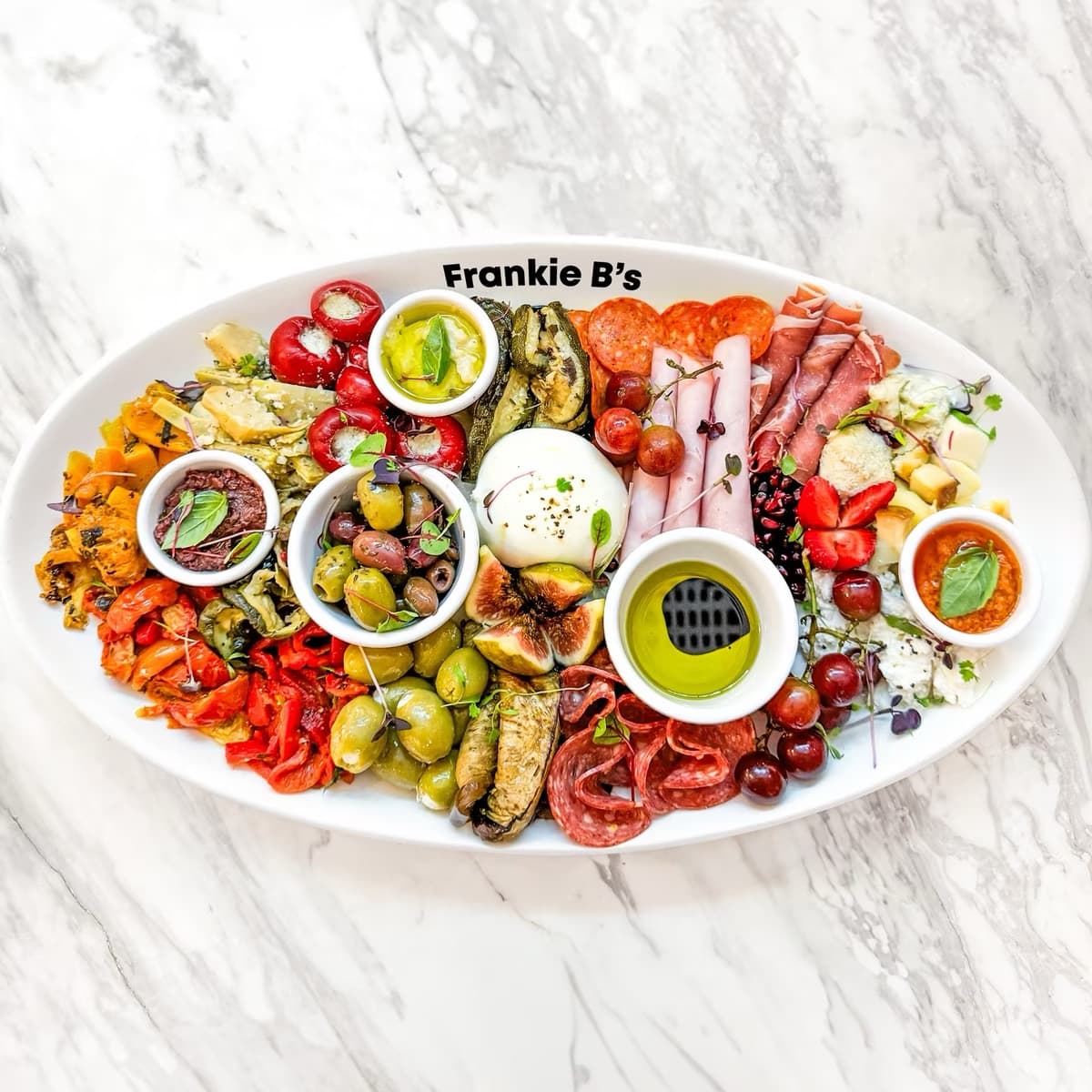 Antipasto Plate featuring a selection of Italian cold cut meats, cheeses, and marinated vegetables with fresh fruits and accompaniments